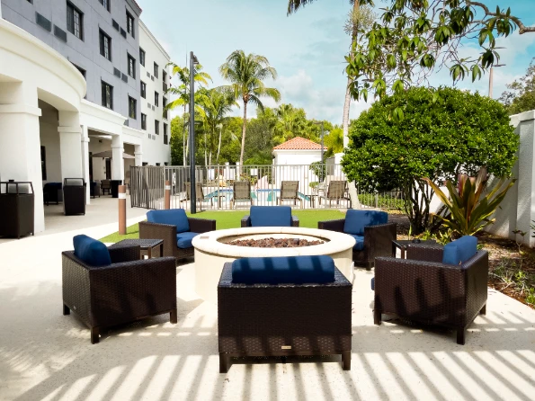 lounge area by the family pool at the Courtyard by Marriott Stuart hotel showing lounging seating by the pool in the outdoor spaces at the hotel in a sunny day