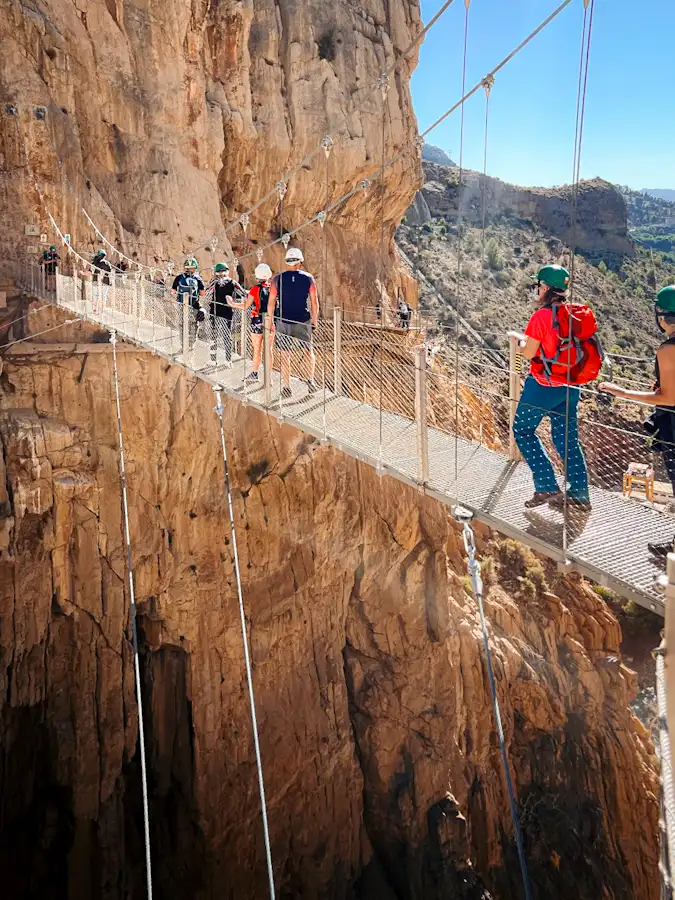 group tour members crossing the new suspended bridge at el caminito del rey in málaga, spain