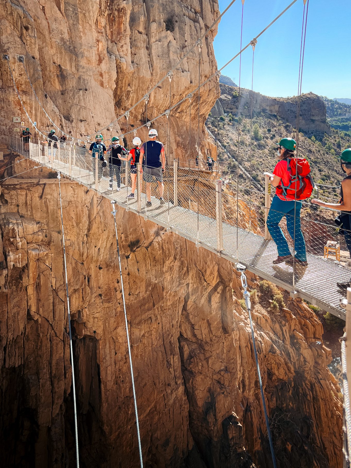 group tour members crossing the new suspended bridge at el caminito del rey in málaga, spain